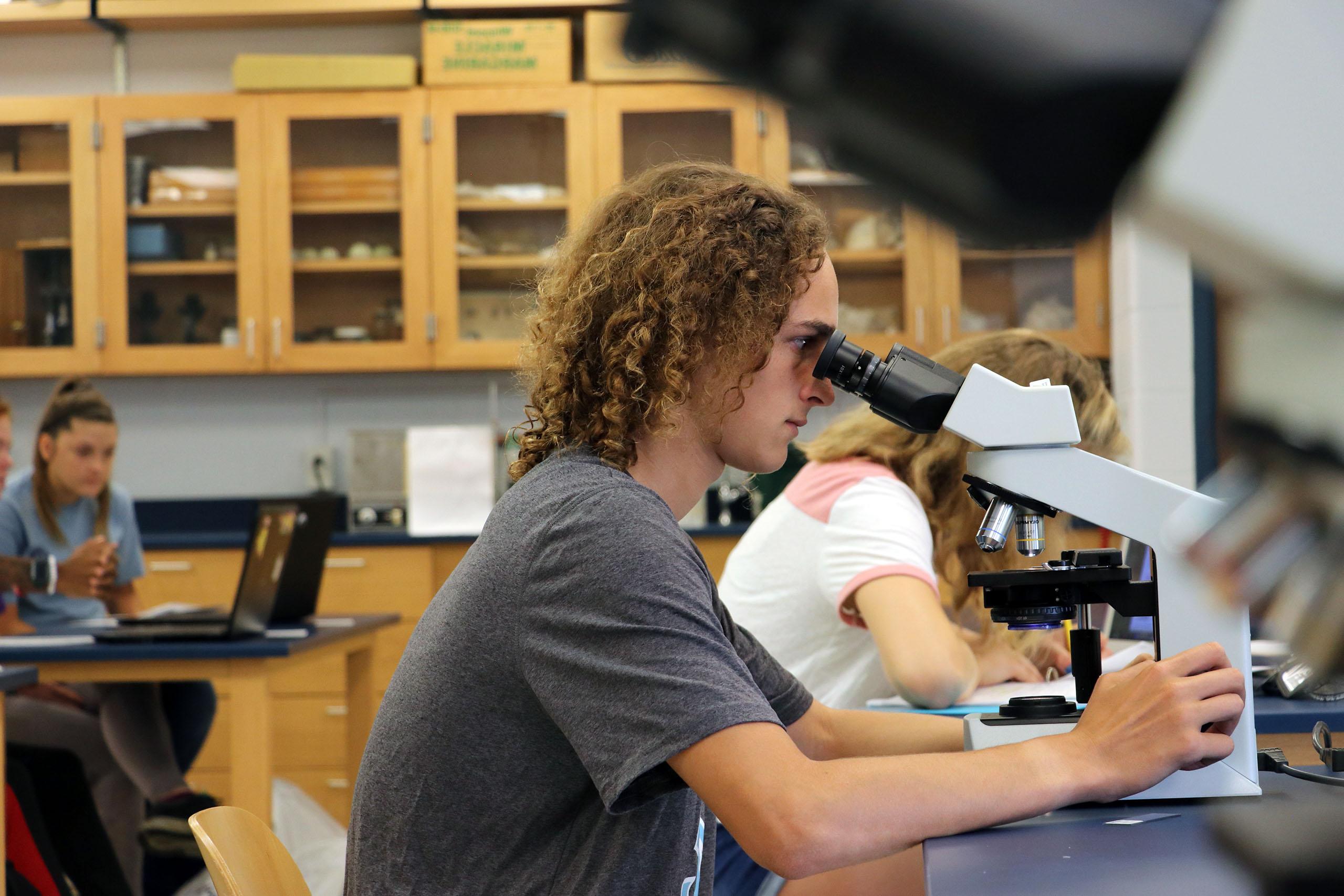 Student looking into a microscope during science class.